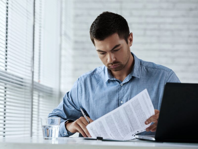 A man with a serious expression reads through documents, taxpayer reading tax documents