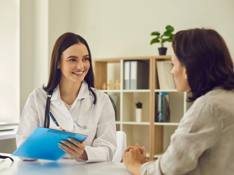 A doctor working in an allied health business happily talks to a patient during outpatient consultations