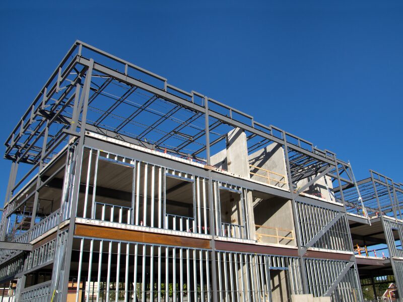 An unfinished commercial property building, metal and concrete exposed, building set against the backdrop of a bright, clear sky