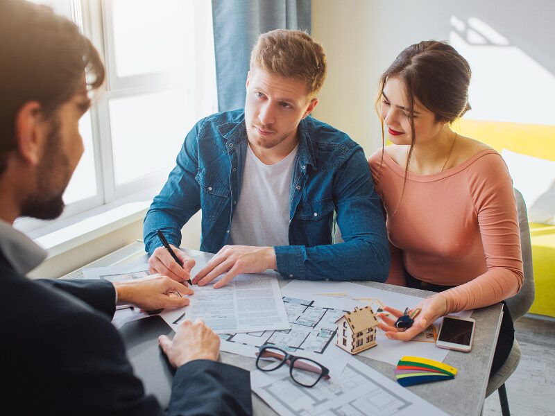 A couple meeting a mortgage broker or lender to refinance their home loan