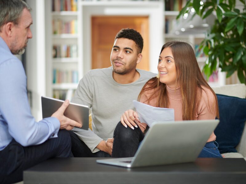 A business-owning couple meet with a mortgage broker or lender to discuss their home loan options and how to qualify