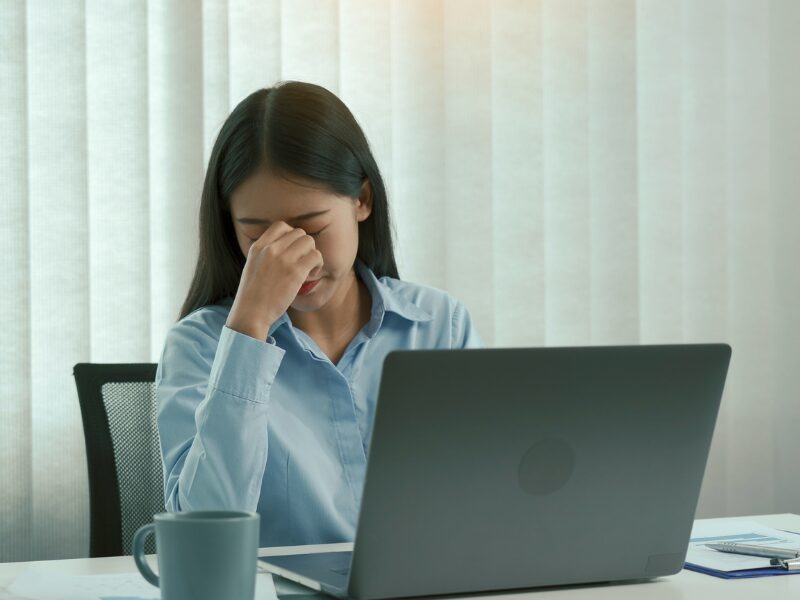 Stressed woman working on her laptop, woman with her hand on her face, rejected home loan applicant