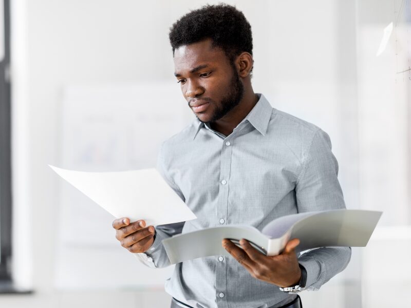 A man with a serious and stressed expression reads a document, applicant reading his new home loan application after getting rejected