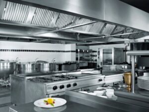 A spotless, empty, stainless steel commercial kitchen, a simple yet beautifully plated dessert in the foreground