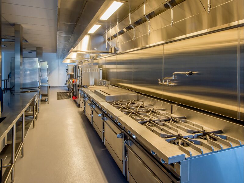 A clean and empty commercial kitchen with stainless steel surfaces and equipment