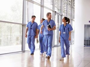 A group of allied health professionals walk through a hallway with large windows