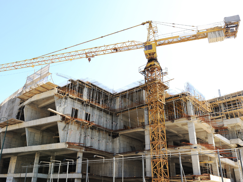 A large yellow crane operating on a building during ongoing construction