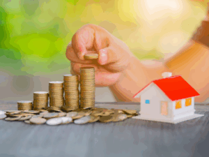 Cropped photo of a person stacking coins in an ascending order next to a miniature model house