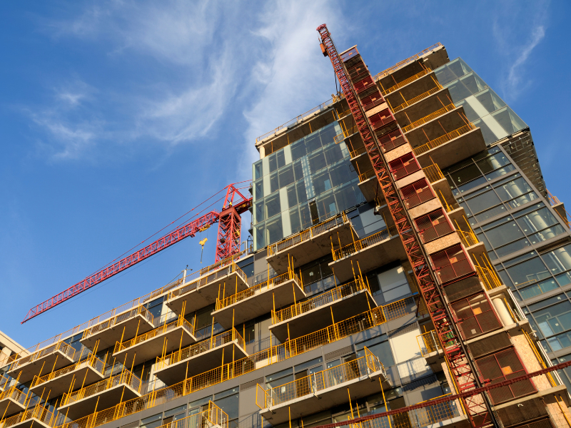 Angled photo of an ongoing building construction project, a red crane visible