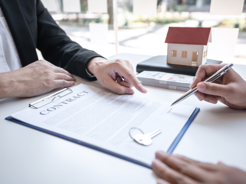 A mortgage broker points at the part of the loan document where the borrower needs to sign