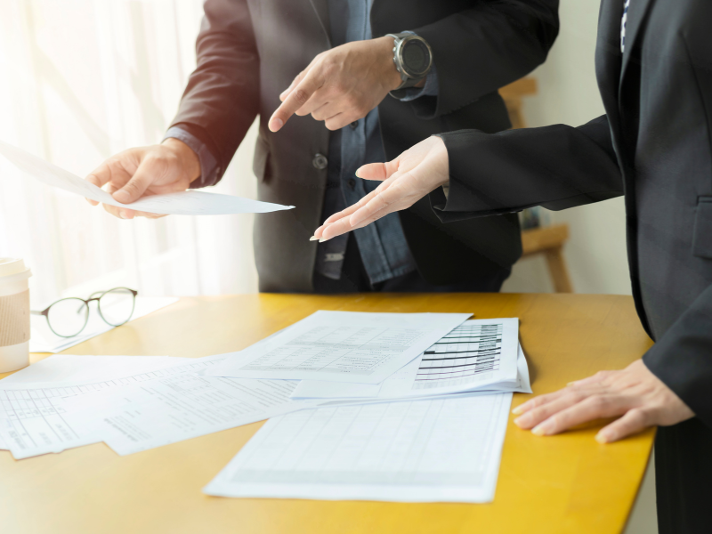 Two business owners discuss interest rates on a low doc home loan, one person holding and pointing to a document