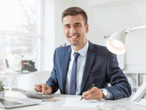 A financial advisor working at his desk smiles directly at the camera