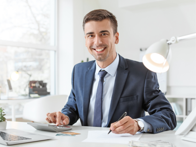 A financial advisor working at his desk smiles directly at the camera