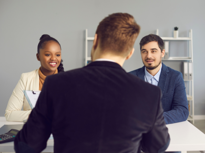 Picture of the back of a mortgage broker, facing two happy clients looking for a low doc home loan
