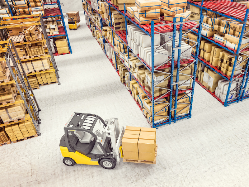 A small forklift carrying boxes inside a large wholesale warehouse
