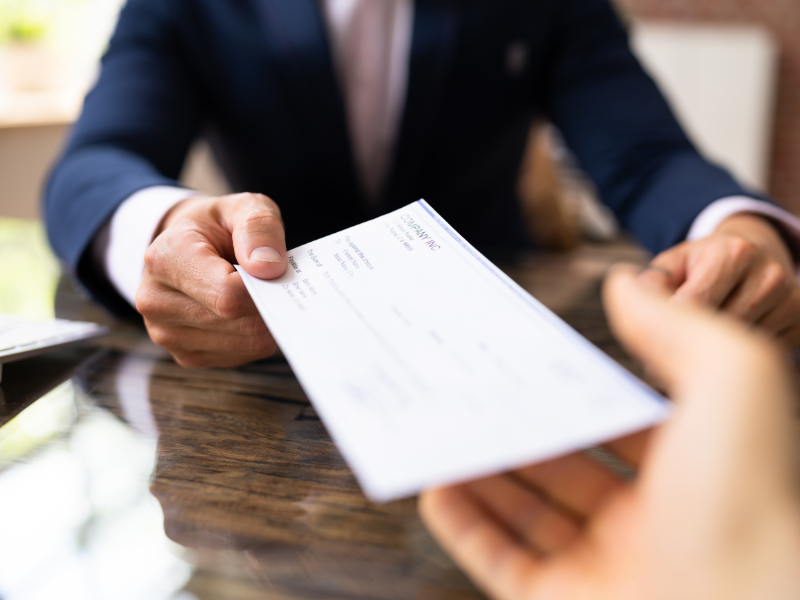 Point-of-view photo of an employee receiving a paycheck from their employer