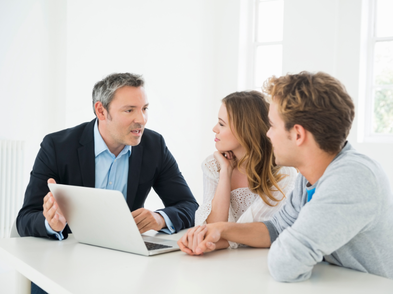 A broker or representative from a private lender talking to a young couple that’s looking for a loan