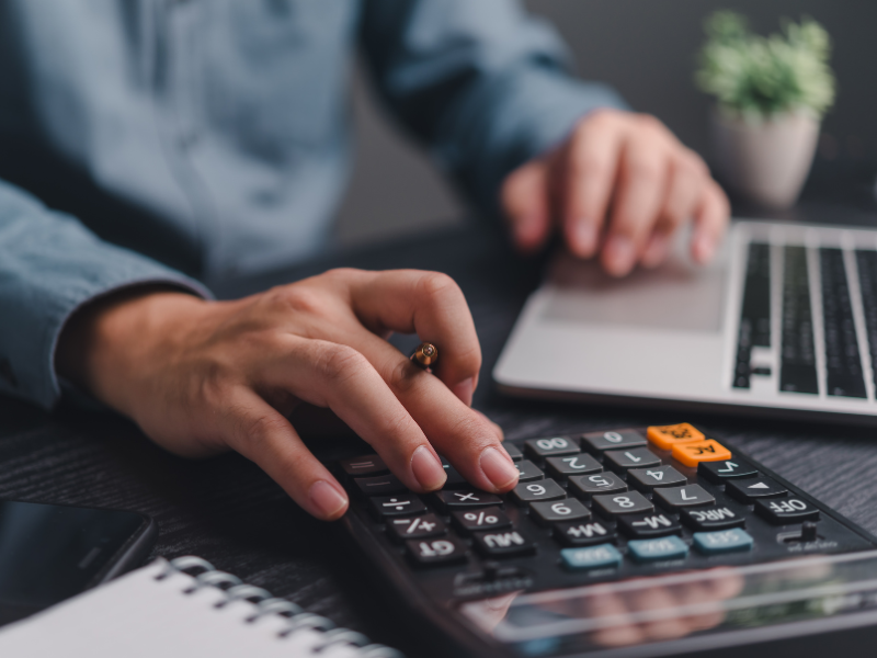 A man’s hand using a calculator, employer calculating payroll for employees