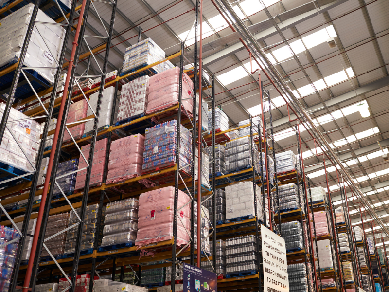 Rows of tall supply shelves inside a brightly lit supplier’s warehouse
