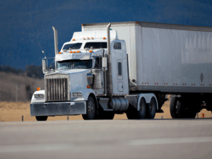 A large white freight truck travelling down the road during the day