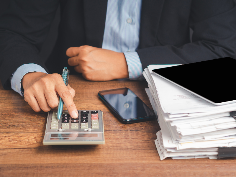 Cropped photo of a man holding a pen while using a calculator, business owner calculating expenses and need for financing