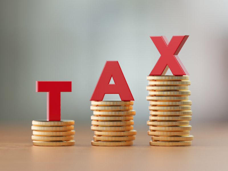 The letters T, A, and X each on top of a pile of coins in ascending order of height, concept for large tax debt