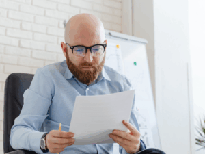 A man in glasses reads documents, reading about payment plans for unpaid super