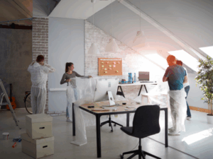 A group of workers cover an office with plastic in preparation for a renovation