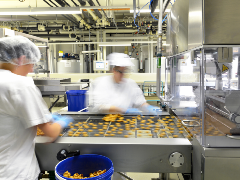 Two factory workers processing food using large machinery in a factory, motion blur photo