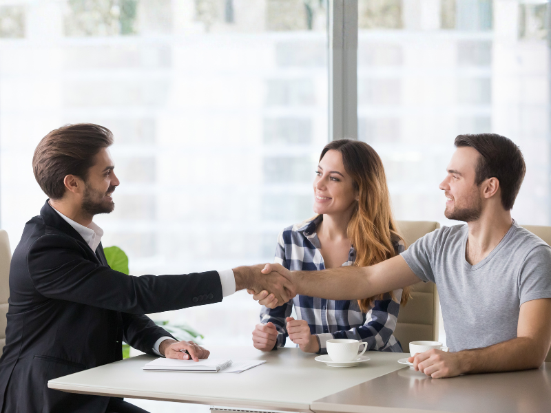 A mortgage broker shakes hands with a business owner, agreeing on a loan product this 2026
