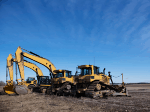 Several large yellow excavators parked at a construction site, striking blue skies in the background