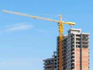 A large yellow crane and a building under construction set against the background of clear blue skies