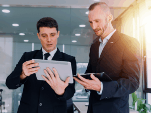 A mortgage broker shows details about working capital loans on his electronic tablet to a client