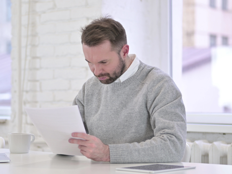 A man closely examines a document, a business director reading a director penalty notice from the ATO