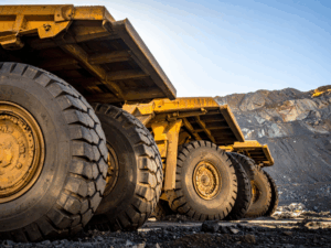 A row of yellow heavy construction equipment, zoomed in on the wheels