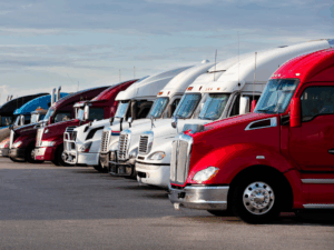 A fleet of red, white, and silver freight trucks parked next to each other at a lot