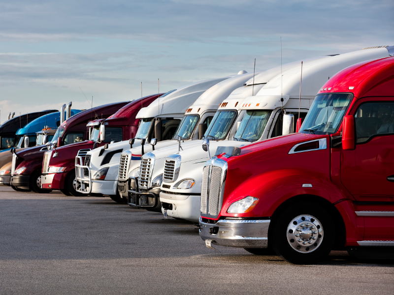 A fleet of red, white, and silver freight trucks parked next to each other at a lot
