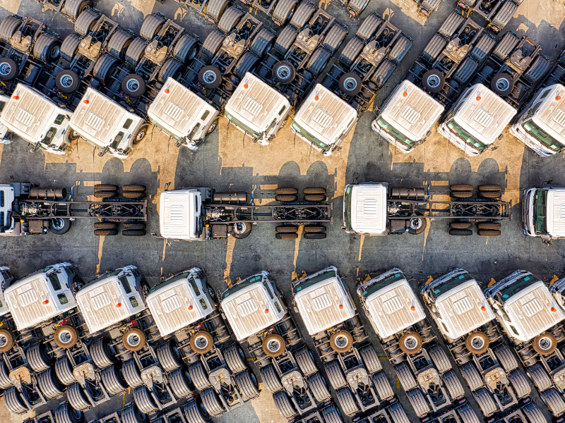 A large fleet of freight trucks parked at a lot, drone shot or aerial view