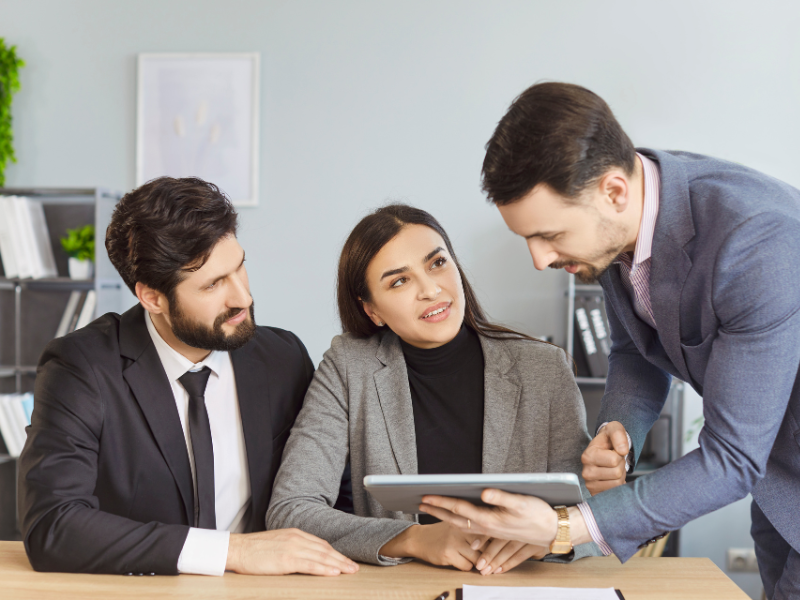 A mortgage broker meets with two clients and discusses large tax debt loan options