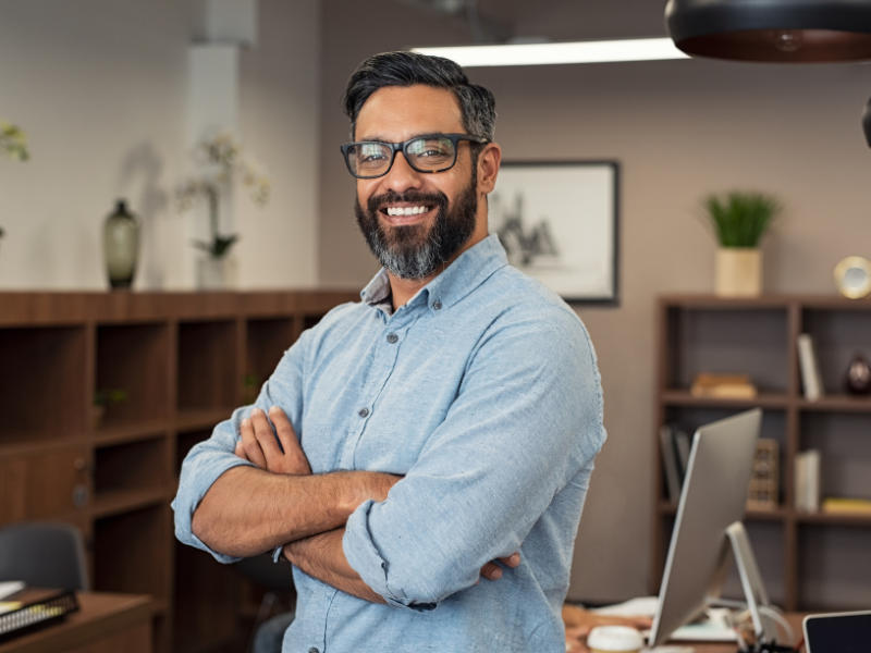 A man smiling at the camera with his arms crossed, a business owner happy about a business line of credit solution