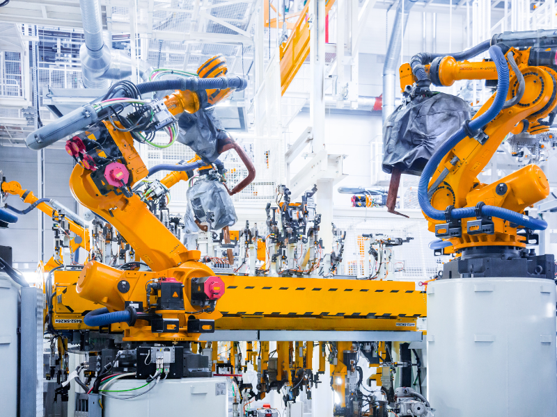 Robotic arms inside a brightly lit plastics manufacturing plant