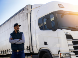 Transport company owner posing next to a large white freight truck