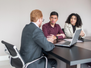 Two business owners meet with a mortgage broker to talk about private emergency loans