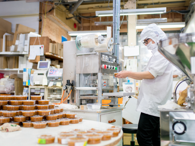 Factory worker at a wholesale food supplier plant packaging food tubs