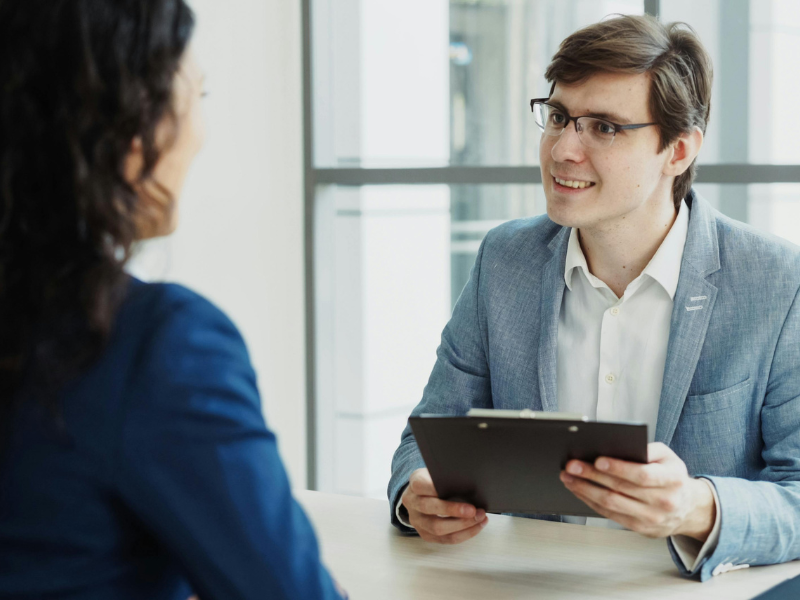 Mortgage broker holding a clipboard discusses emergency loan options with a business owner