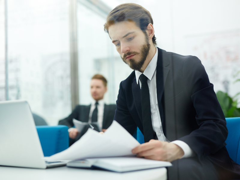 A man in an office reads documents, reading about withholding tax for employees