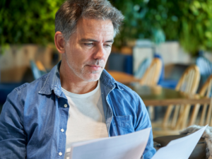 A man reads documents, reading details of tax debts to the ATO