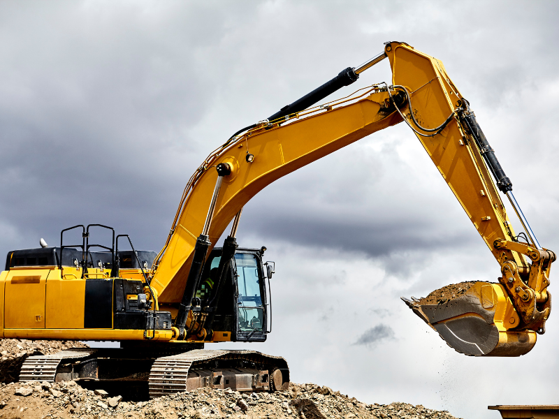 A large yellow excavator, cloudy skies in the background