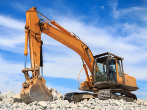 An orange excavator moving loose rocks at a construction site