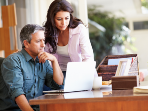 A man and a woman intently read the monitor of a laptop, business owners learning about the GIC and SIC